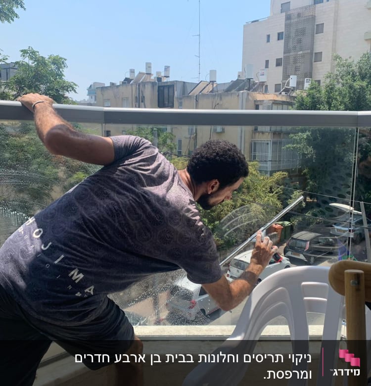 אדם מנקה חלון זכוכית עם מגב וסבון